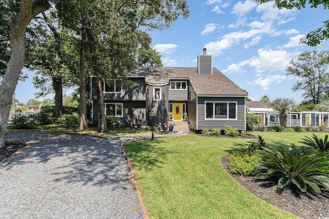 view of front of house featuring a chimney, a front yard, and roof with shingles