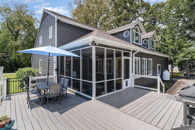 wooden terrace with outdoor dining area and a sunroom