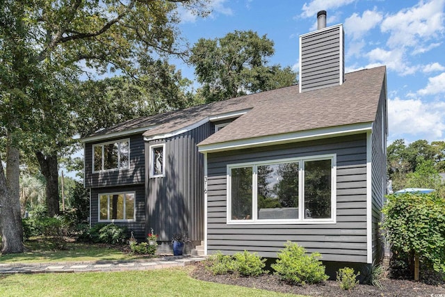 view of front of property featuring a chimney and a shingled roof