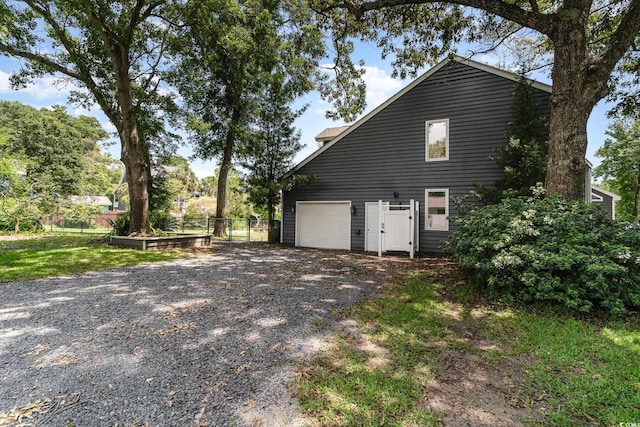 view of home's exterior featuring gravel driveway and fence