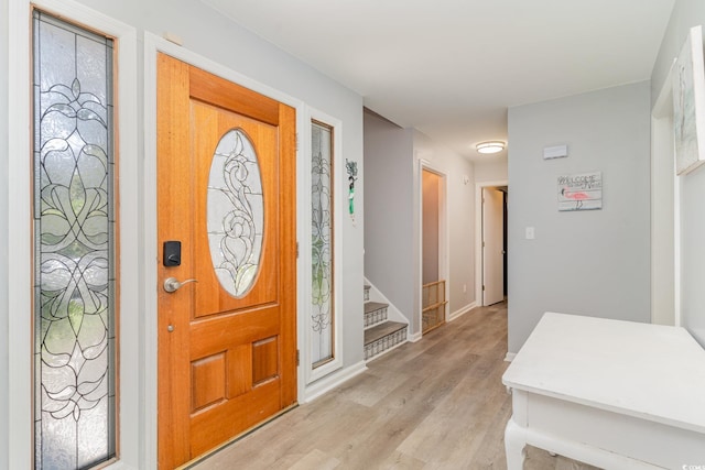 foyer featuring stairway, baseboards, and light wood finished floors