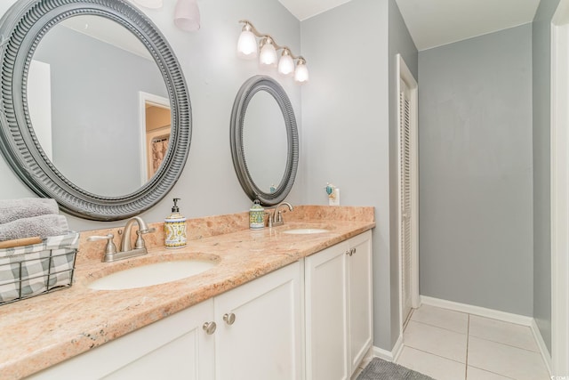 bathroom with a sink, baseboards, double vanity, and tile patterned flooring