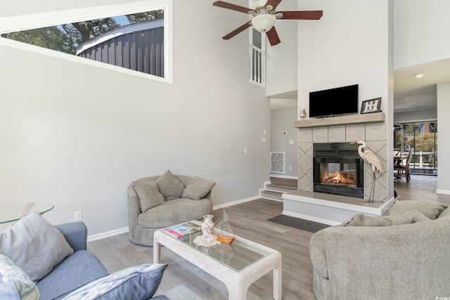 living area featuring visible vents, wood finished floors, baseboards, ceiling fan, and a tile fireplace