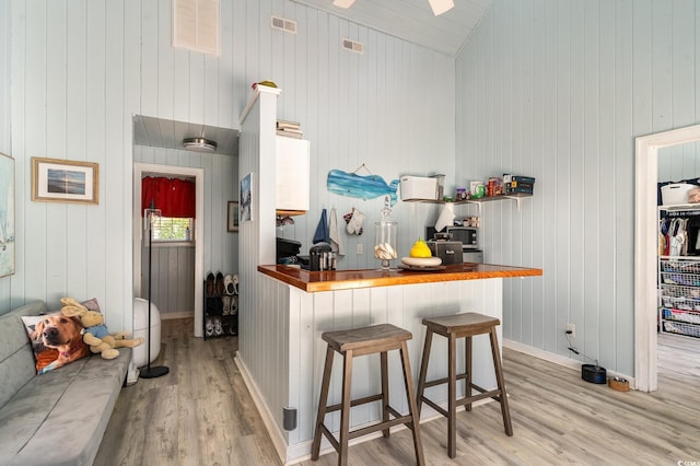 kitchen featuring visible vents, wooden counters, lofted ceiling, and wood finished floors