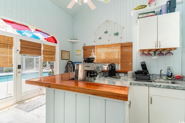 kitchen featuring a peninsula, white cabinetry, ceiling fan, and a sink