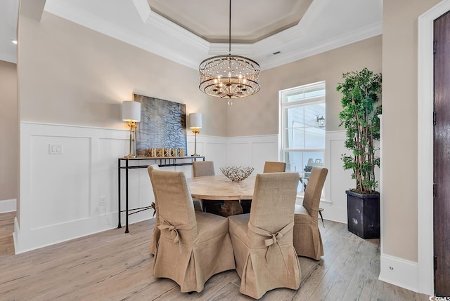 410 44th Ave N, Myrtle Beach, SC 29577 - dining room featuring a raised ceiling, a chandelier, crown molding, light wood-style flooring, and a wainscoted wall