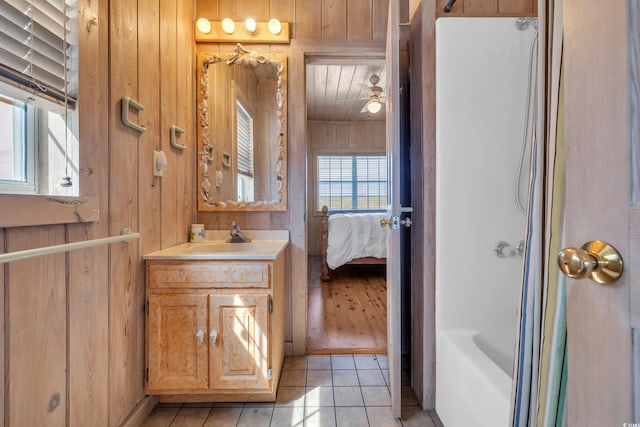 bathroom featuring a ceiling fan, connected bathroom, wooden walls, vanity, and tile patterned flooring