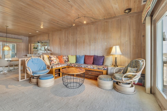 carpeted living area with wood ceiling and wooden walls