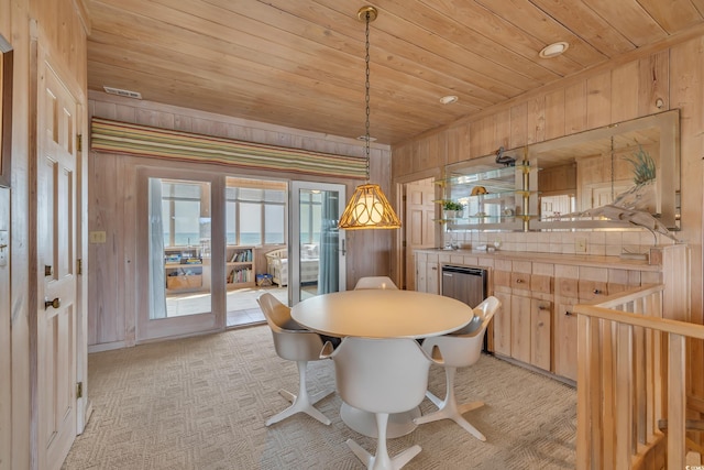 dining room featuring wooden ceiling, light carpet, and wood walls