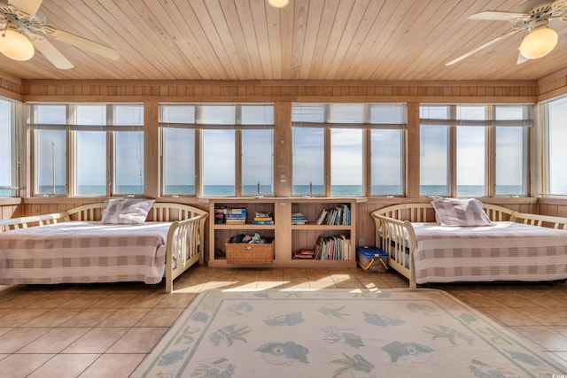 bedroom featuring light tile patterned floors, wood walls, a water view, and wood ceiling