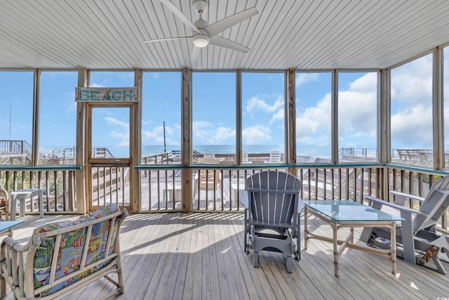 sunroom featuring plenty of natural light, a ceiling fan, and a water view