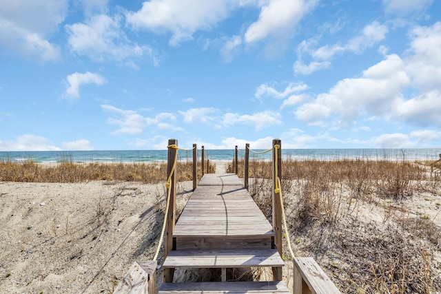 view of home's community featuring a water view, a beach view, and a boat dock