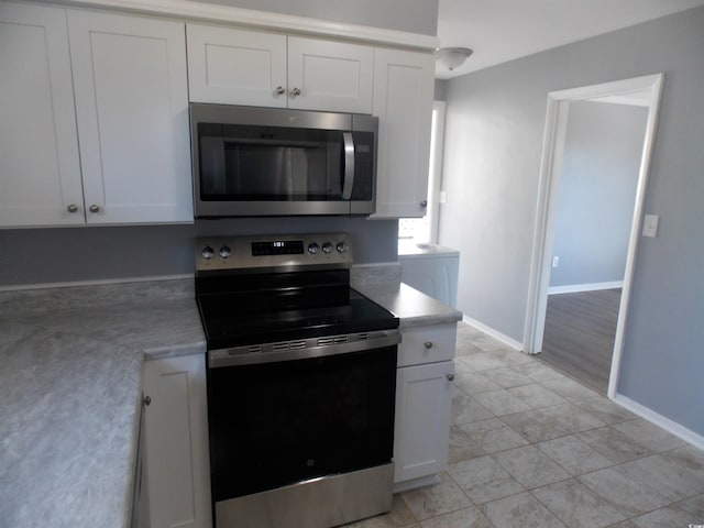 kitchen with light countertops, electric range, stainless steel microwave, and white cabinets