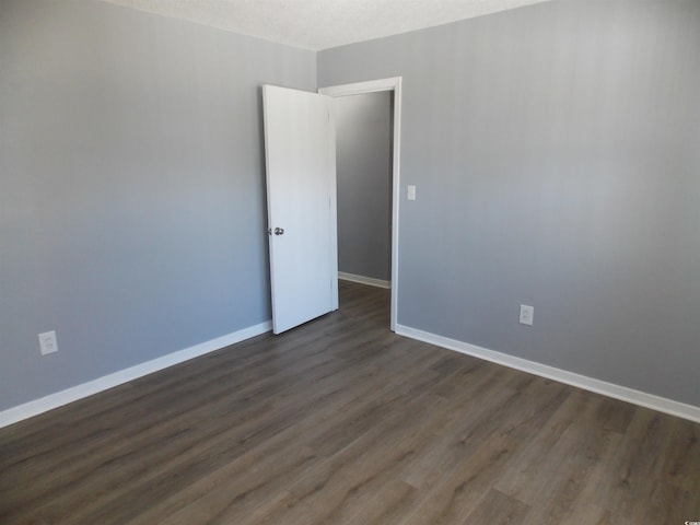 spare room featuring baseboards, dark wood finished floors, and a textured ceiling