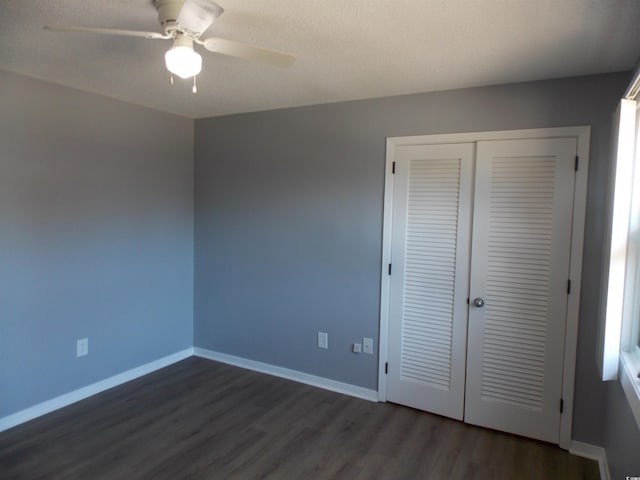 unfurnished bedroom with a textured ceiling, baseboards, dark wood-style flooring, and a closet