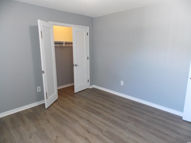 unfurnished bedroom featuring a closet, baseboards, and wood finished floors