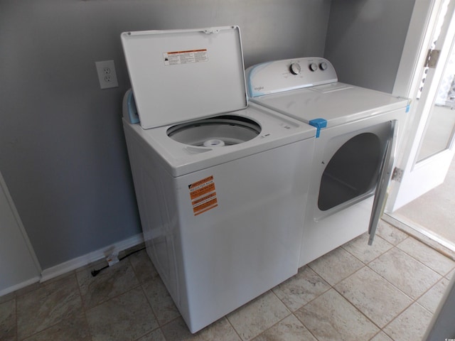 clothes washing area with washer and clothes dryer and baseboards