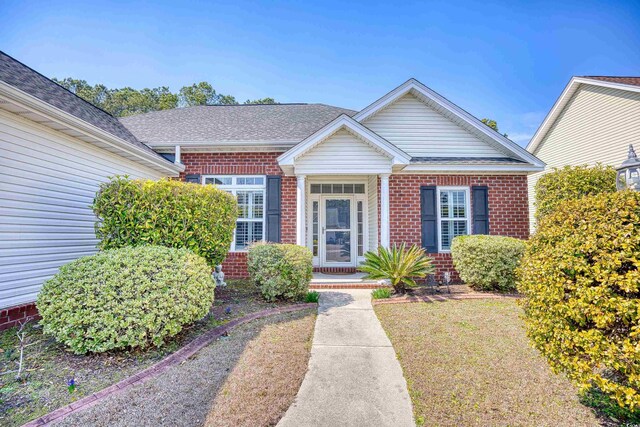 view of front of home with brick siding and roof with shingles