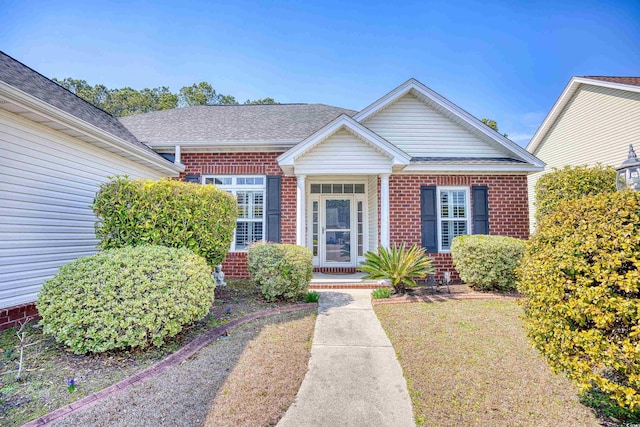 view of front of home featuring brick siding and roof with shingles