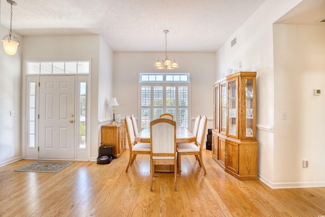 dining space with a notable chandelier, visible vents, light wood-type flooring, and a wealth of natural light