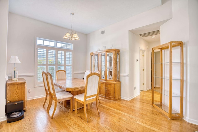 dining area with baseboards, visible vents, light wood finished floors, and a chandelier