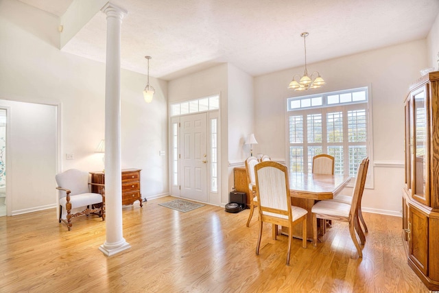 dining space featuring baseboards, light wood-type flooring, an inviting chandelier, and decorative columns