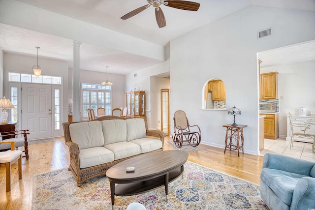 living room with light wood-style flooring, high vaulted ceiling, baseboards, and decorative columns