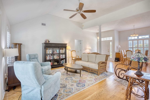 living area featuring visible vents, ceiling fan with notable chandelier, light wood-type flooring, and lofted ceiling