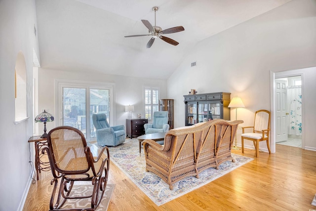 living room featuring visible vents, high vaulted ceiling, a ceiling fan, light wood finished floors, and baseboards