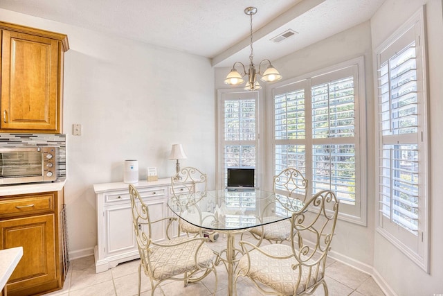 dining space with a textured ceiling, a healthy amount of sunlight, visible vents, and a chandelier