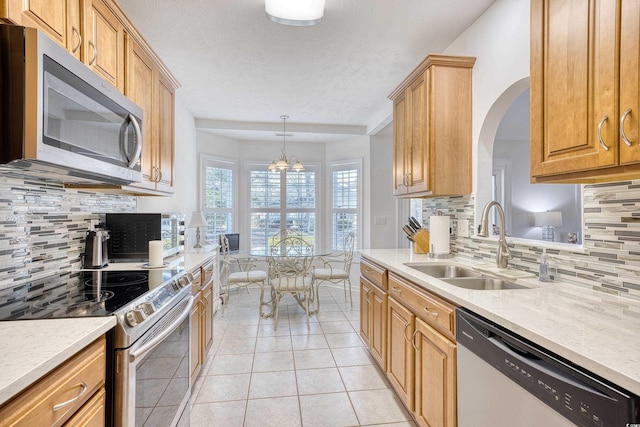 kitchen with a sink, decorative backsplash, appliances with stainless steel finishes, and light tile patterned floors