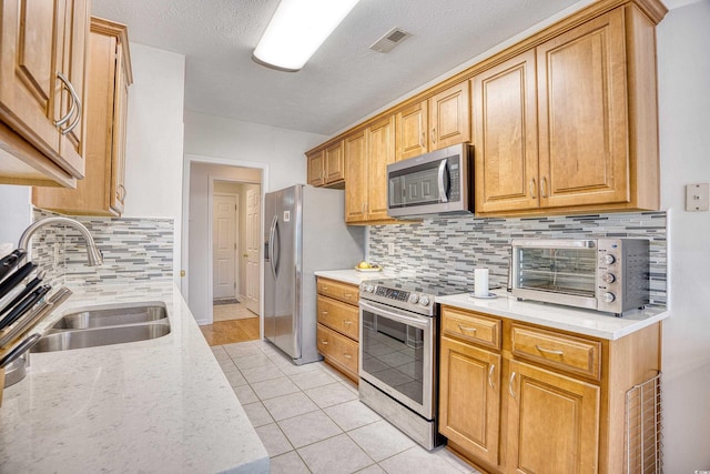 kitchen featuring visible vents, a toaster, light tile patterned floors, appliances with stainless steel finishes, and a sink