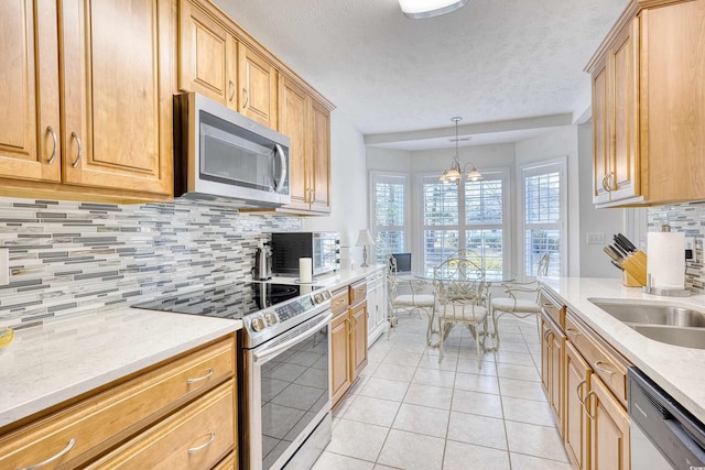 kitchen featuring tasteful backsplash, a chandelier, light tile patterned floors, stainless steel appliances, and a sink