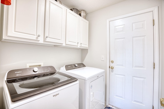 laundry room with cabinet space, a textured ceiling, and washer and clothes dryer