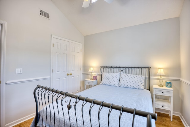 bedroom with visible vents, lofted ceiling, wood finished floors, a closet, and a ceiling fan