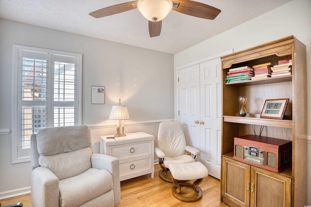 living area featuring a textured ceiling, ceiling fan, and light wood finished floors