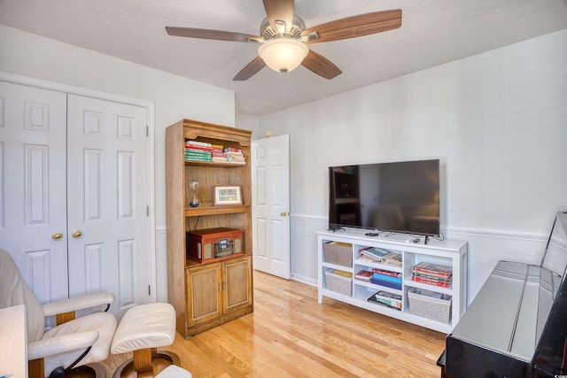 sitting room with light wood-style floors, a ceiling fan, and a textured ceiling