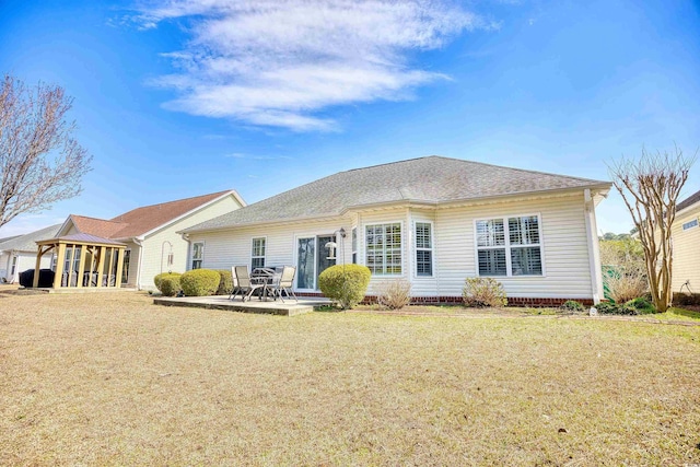 back of property featuring a yard, a patio, and a shingled roof