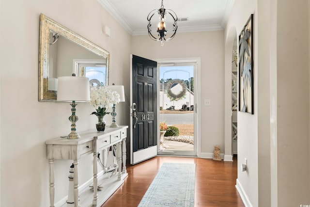 foyer entrance with baseboards, visible vents, ornamental molding, wood finished floors, and an inviting chandelier