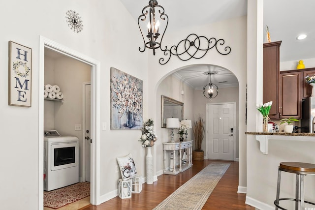 entryway with a notable chandelier, dark wood-type flooring, baseboards, washer / clothes dryer, and crown molding