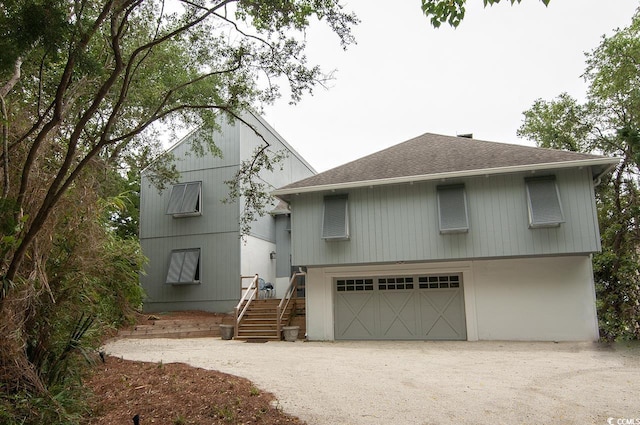 view of front of house featuring an attached garage, roof with shingles, and dirt driveway