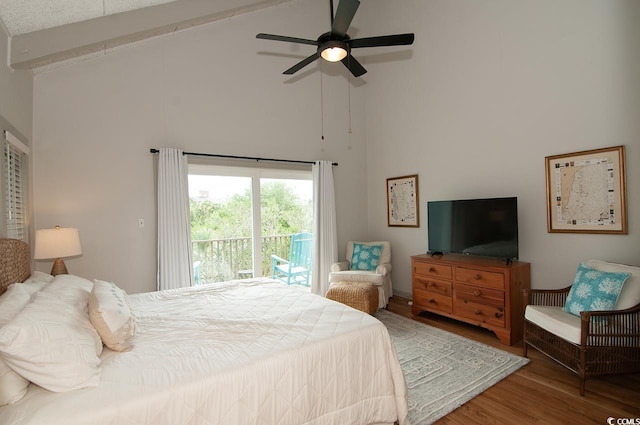 bedroom featuring access to exterior, high vaulted ceiling, a ceiling fan, and wood finished floors