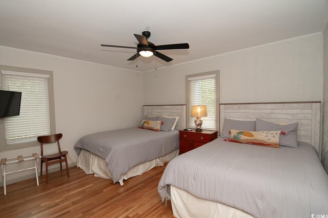 bedroom featuring baseboards, wood finished floors, a ceiling fan, and ornamental molding