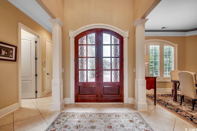 foyer entrance featuring arched walkways, french doors, crown molding, tile patterned flooring, and ornate columns