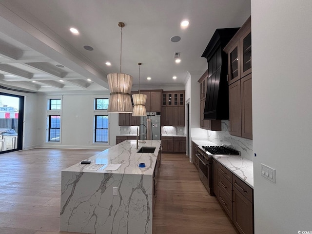 kitchen featuring stainless steel appliances, a sink, light wood-style flooring, and decorative backsplash