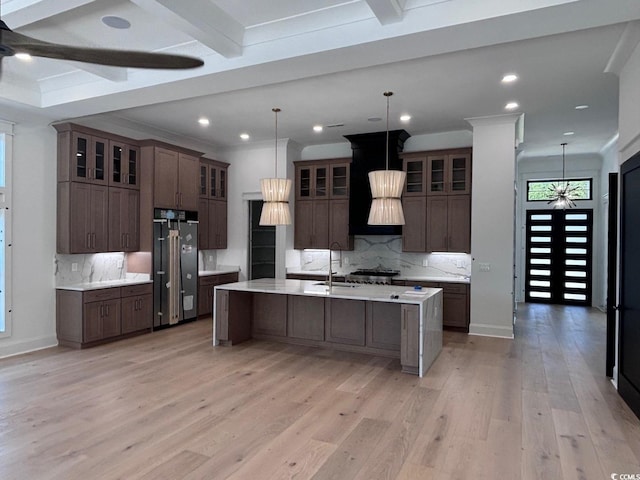 kitchen featuring light wood finished floors, tasteful backsplash, light countertops, a large island with sink, and high end refrigerator