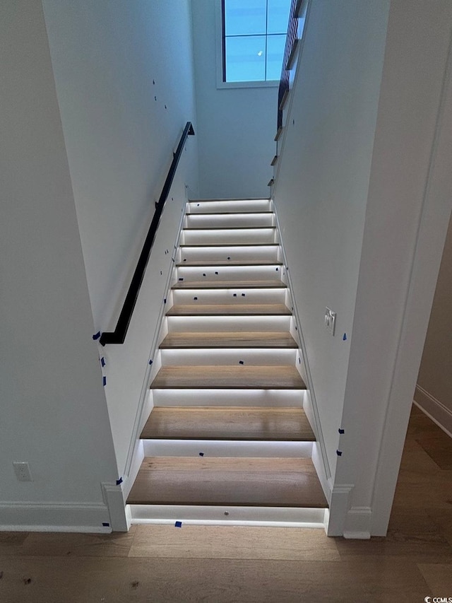 stairway with wood finished floors and baseboards