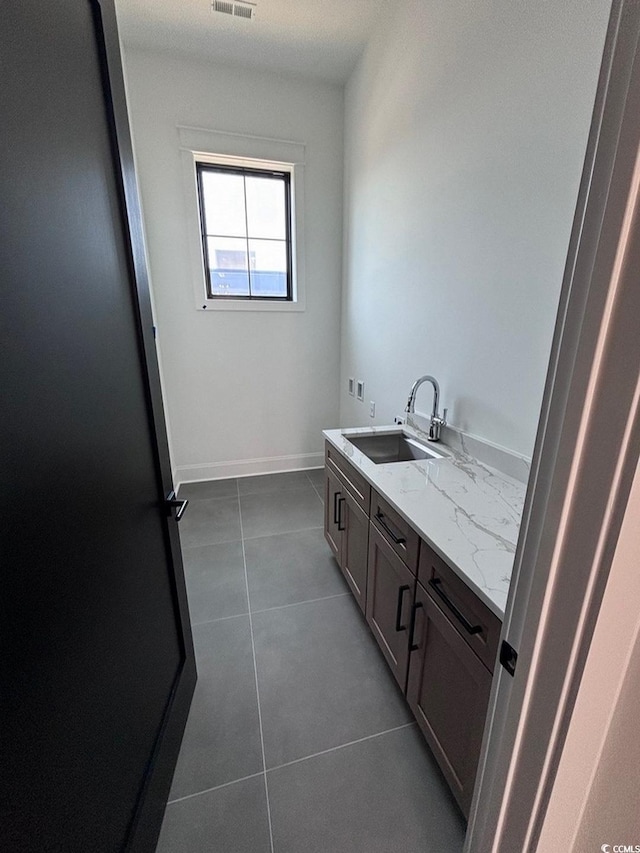 bathroom featuring a sink, visible vents, baseboards, tile patterned floors, and double vanity