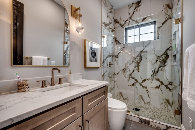 bathroom featuring toilet, a marble finish shower, and vanity