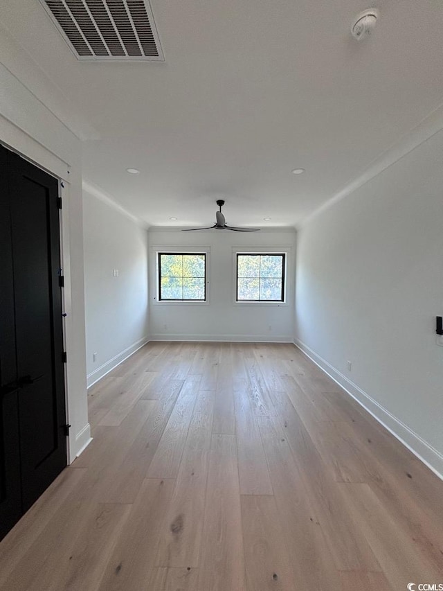 empty room with light wood-style floors, baseboards, visible vents, and ceiling fan